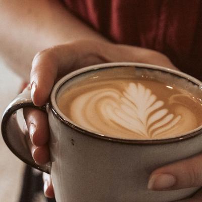 A cup of coffee being held, hand shot.