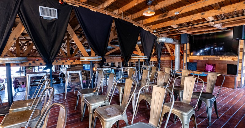 Interior - metal chairs arranged in rows, high tables, chairs; wooden beams on the ceiling