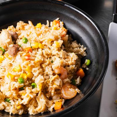Fried rice with vegetables and meat in a takeout container.