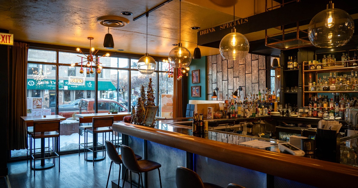 Interior with a modern design featuring a counter, stools, pendant lights and large windows