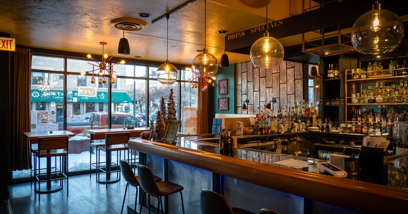 Interior with a modern design featuring a counter, stools, pendant lights and large windows