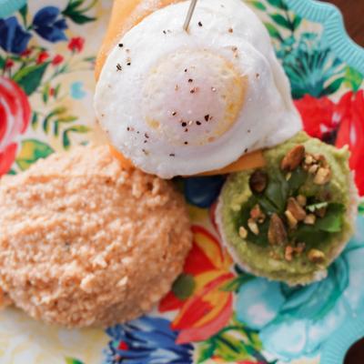 Poached egg, cheese grits, and a biscuit topped with guacamole, and nuts.
