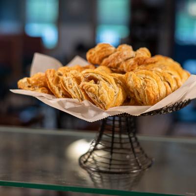 A stack of flaky, golden-brown pastries sits on a wire stand lined with parchment paper.