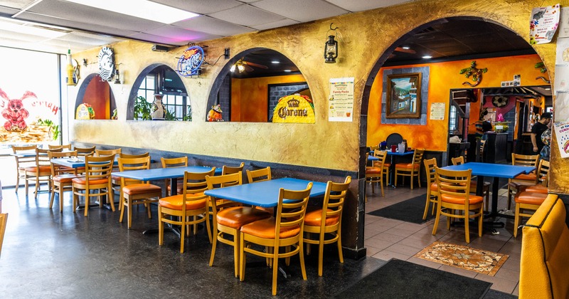 Cozy restaurant interior with vibrant orange-gold walls and blue tables