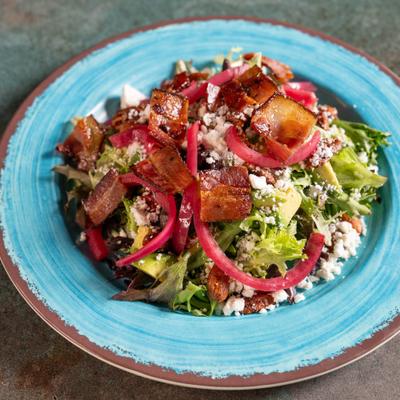 Salad with lettuce, goat cheese, bacon, and pickled red onion.