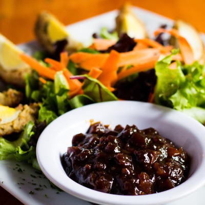 Scotch eggs quartered into slices on a plate with a green salad and a dish of pickled relish