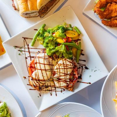 Chicken caprese sandwich with mozzarella, tomato, balsamic drizzle, and mixed vegetables on the side