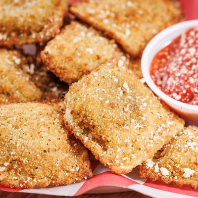Toasted ravioli with marinara on the side, close up.