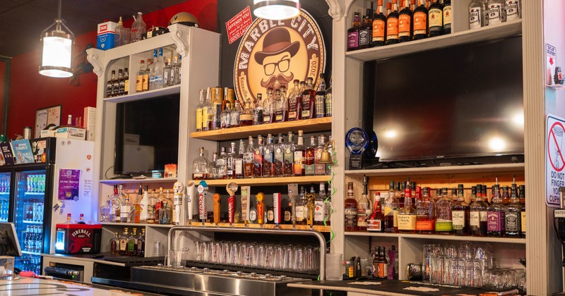 Interior, bar area, fully stocked shelves with various types of liquor, front view