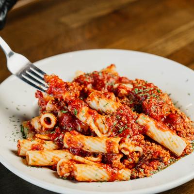 Forkful of rigatoni pomodoro being lifted from the plate.