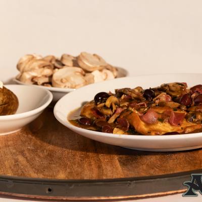 Chicken Cacciatore with a bowl of sliced mushrooms in the background.