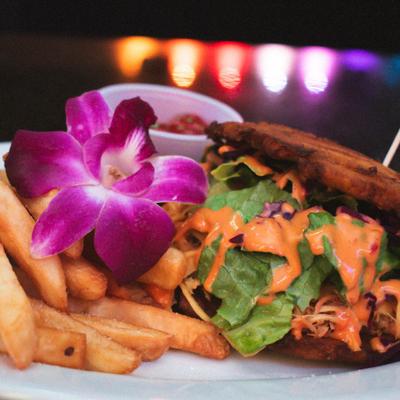 Crispy plantain sandwich, with red cabbage, lettuce, pickles, onions, peppers, sriracha, and fries.