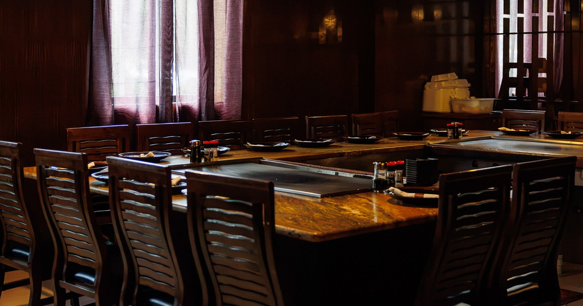 Interior dining area with wooden teppanyaki-style table, equipped with a built-in grill