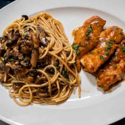 Chicken Marsala served with spaghetti topped with mushrooms.