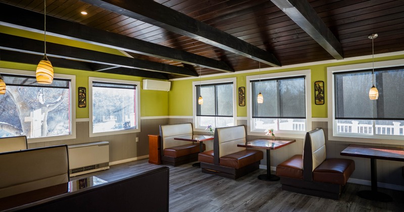 Restaurant interior with booth seating, wooden ceiling beams, and pendant lights.