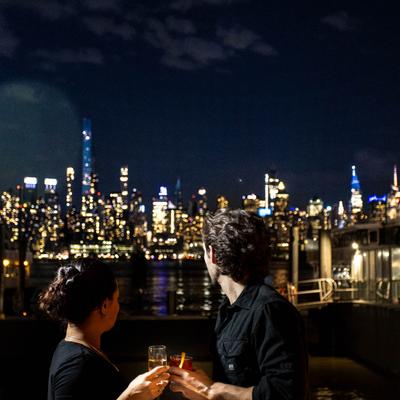 Two people enjoying their drinks and a view of the evening skyline.