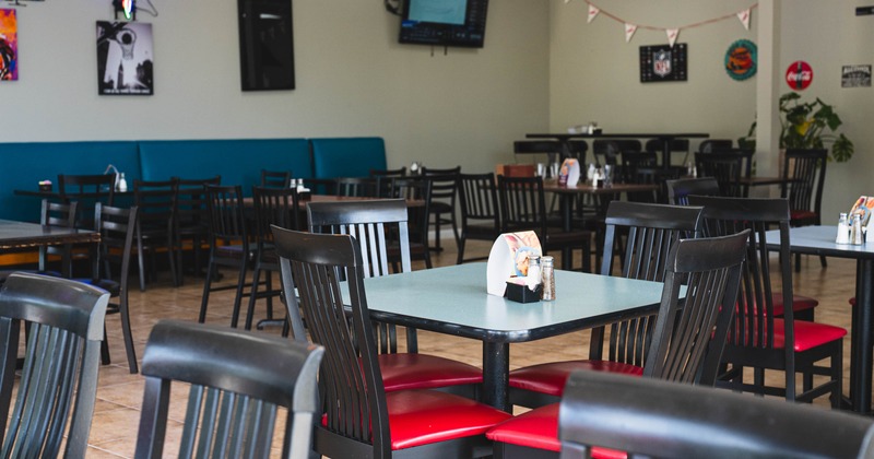 Interior with tables, red-chaired seating and teal booth along a wall.