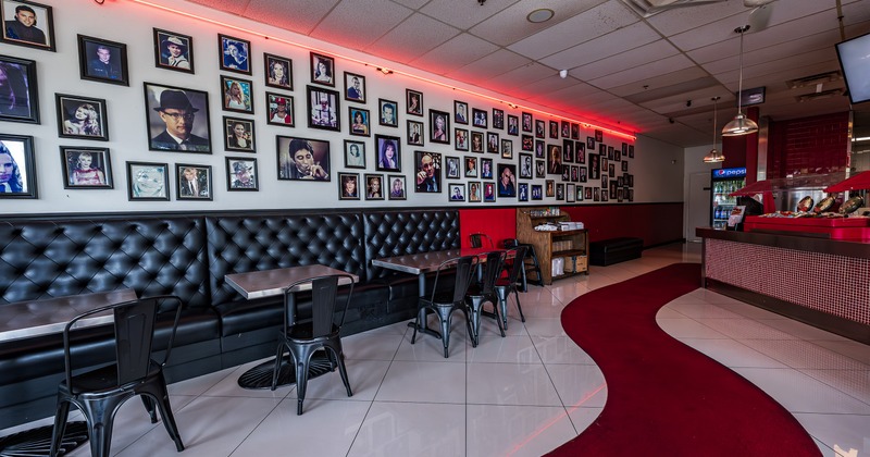 Interior, upholstered seating, tables and chairs, framed photographs of celebrities on the wall