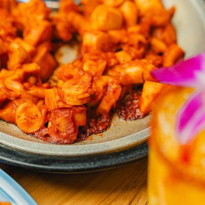 Spicy octopus with a cocktail in the foreground.