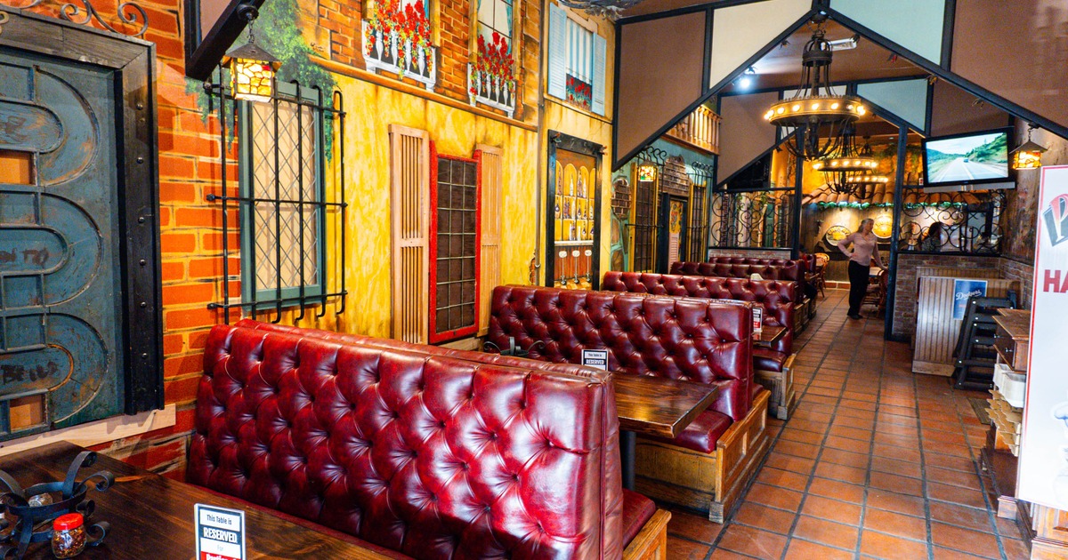 Interior of a restaurant with red leather booths, painted mural walls, and terracotta tile flooring