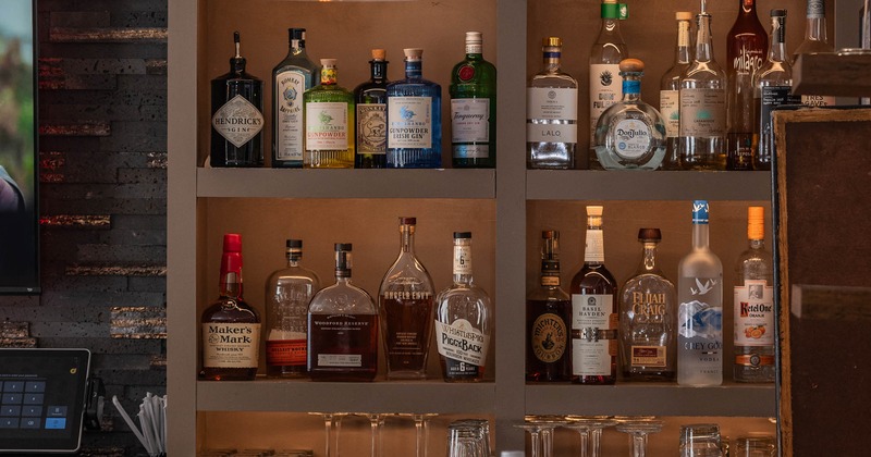 Shelving unit behiund the bar with a variety of liquor bottles