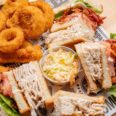 Turkey Club Sandwich served with onion rings and coleslaw.