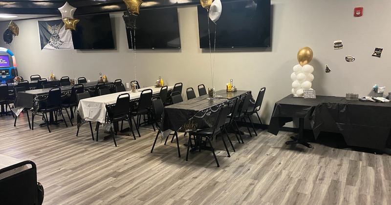 Party room with tables set up for an event, covered in black and white tablecloths