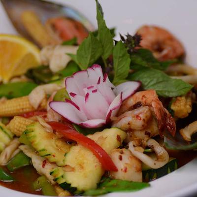 Mixed seafood in a sauce with zucchini, baby corn, mushroom, basil leaves and bell pepper.