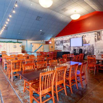 Spacious dining room with wooden tables and chairs under string lights.