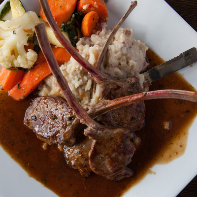 Rack of lamb with mashed potatoes and cooked vegetables.