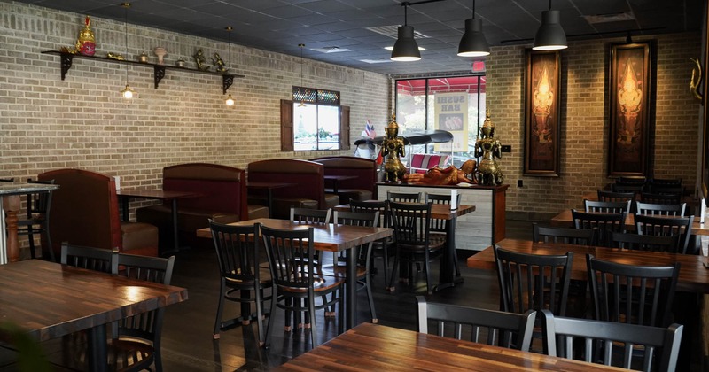 Interior of a restaurant with brick walls, wooden tables, and red cushioned booths