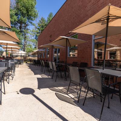 Sunny outdoor patio lined with tables and umbrellas.