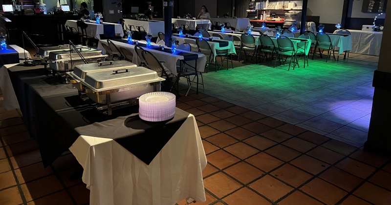 Banquet hall with buffet tables covered in black and white linens, chafing dishes, and plates