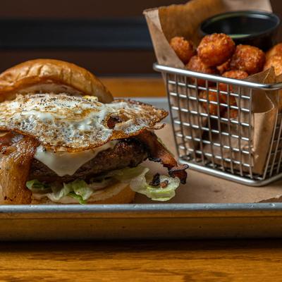 Burger with bacon and fried egg, served with tater tots.