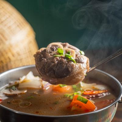 A steaming bowl of oxtail soup featuring tender meat in a savory broth.