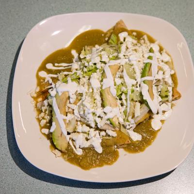 Enchiladas Verdes topped with queso fresco, crema, and sliced avocado.