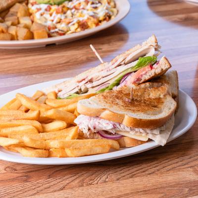 Baked turkey sandwich with lettuce and tomatoes served with fries.