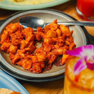 Spicy octopus served with a cocktail with orchid garnish.