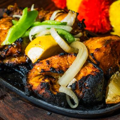 Tandoori chicken pieces with onions and a lemon wedge, close-up.