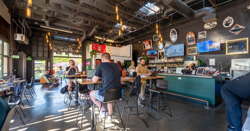 Diner area, bar tables and chairs, bar behind, tv above, guest eating