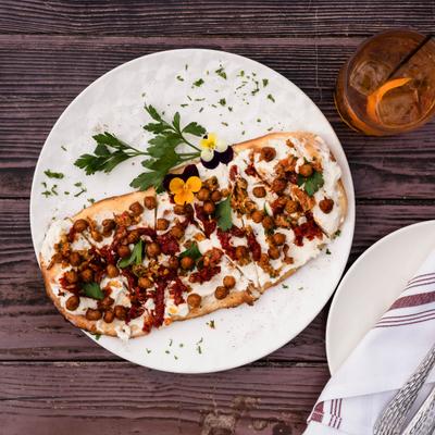Flatbread with goat cheese, sundried tomato, almond, fried chickpea and herbs.