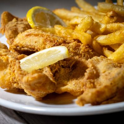 Fried cod with fries and lemon garnish.