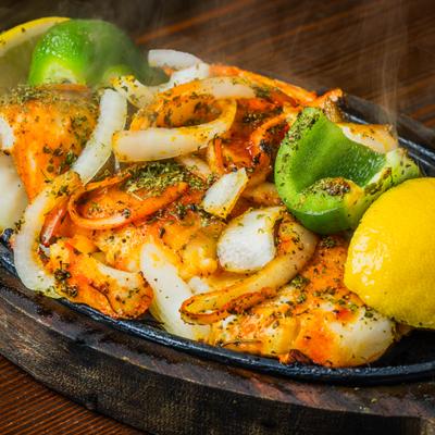 Prawn tikka masala  served in a skillet on a wooden base.
