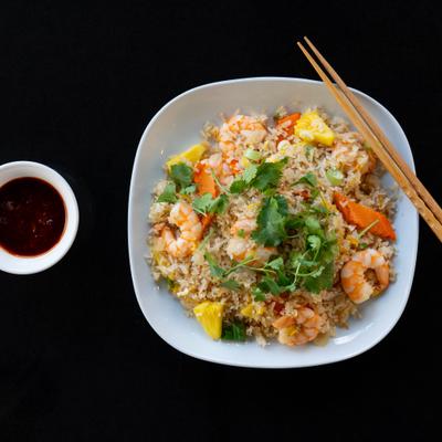 Pineapple fried rice with shrimp on white plate, served with dipping sauce.
