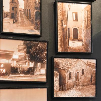 Framed sepia-toned pictures of an old Italian town on a black wall.