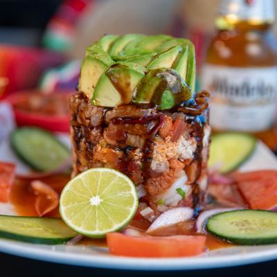The Tower dish - Seafood tostada served on a plate with veggie garnish and lime.