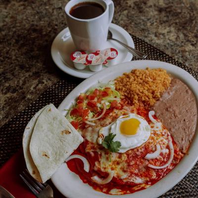 Cheese Enchilada topped with fried egg, served rice, beans, salad and a tortilla.