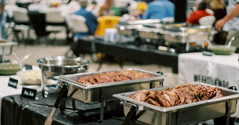 Catering buffet setup withsliced smoked brisket in warming pans