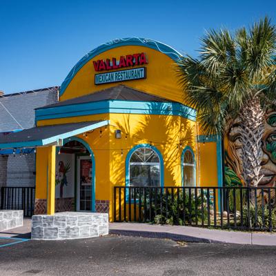 Vallarta Mexican restaurant exterior with a yellow facade and a palm tree.