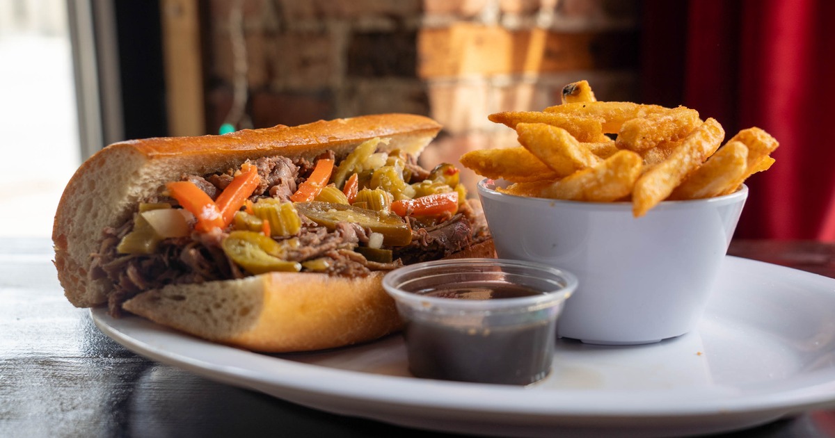 Italian beef sandwich topped with spicy giardiniera, served with fries and au jus
